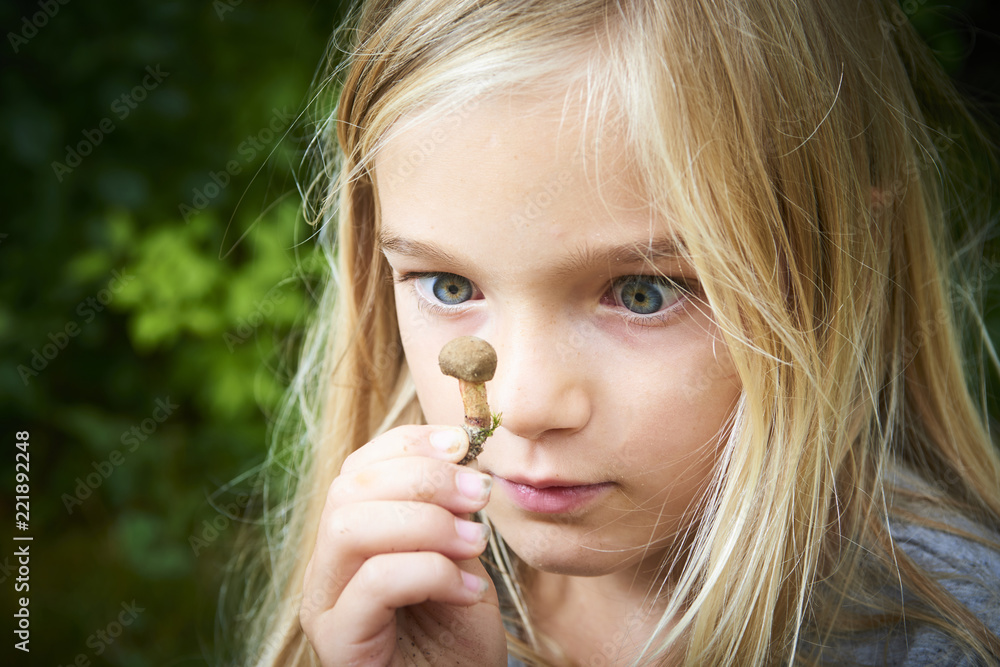 Child blong girl posing in forest and holding fresh picked mushroom (boletus). Selective focus Child blong girl posing in forest and holding fresh picked mushroom (boletus). Selective focus