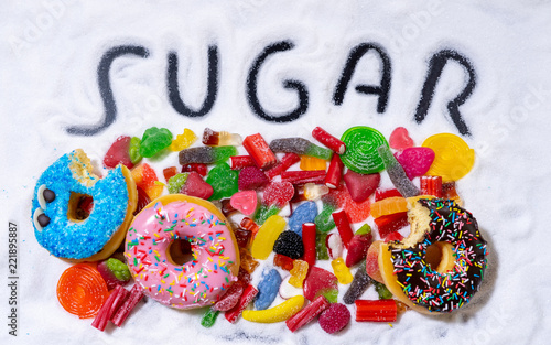 Mix of tempting sweet cakes, donuts and candy with sugar spread and written text in unhealthy nutrition, chocolate abuse sugar addiction concept, body and dental care and health problems..