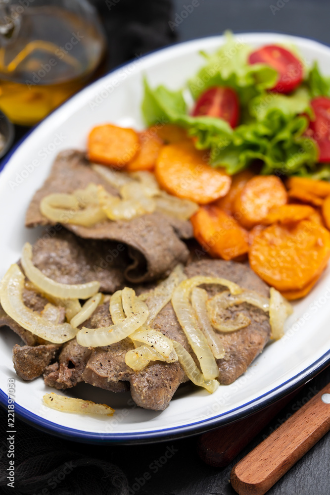 fried liver with onion, sweet potato and salad on white dish fried liver with onion, sweet potato and salad on white dish