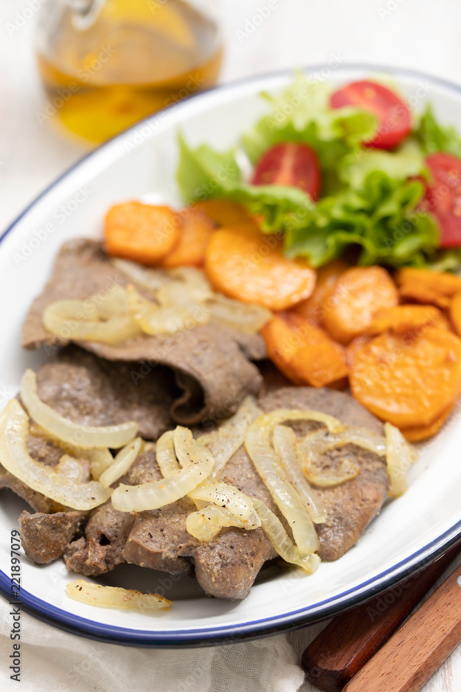 fried liver with onion, sweet potato and salad on white dish fried liver with onion, sweet potato and salad on white dish