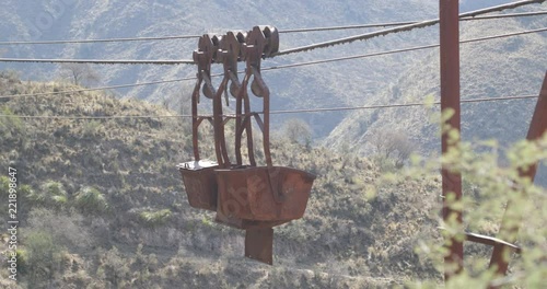 Old Cable Car Chilecito-La Mejicana mine. Detail of hanging wagons from cable. Mountains and vegetation at background moving with the wind. Camera stays still. National Industrial Heritage photo