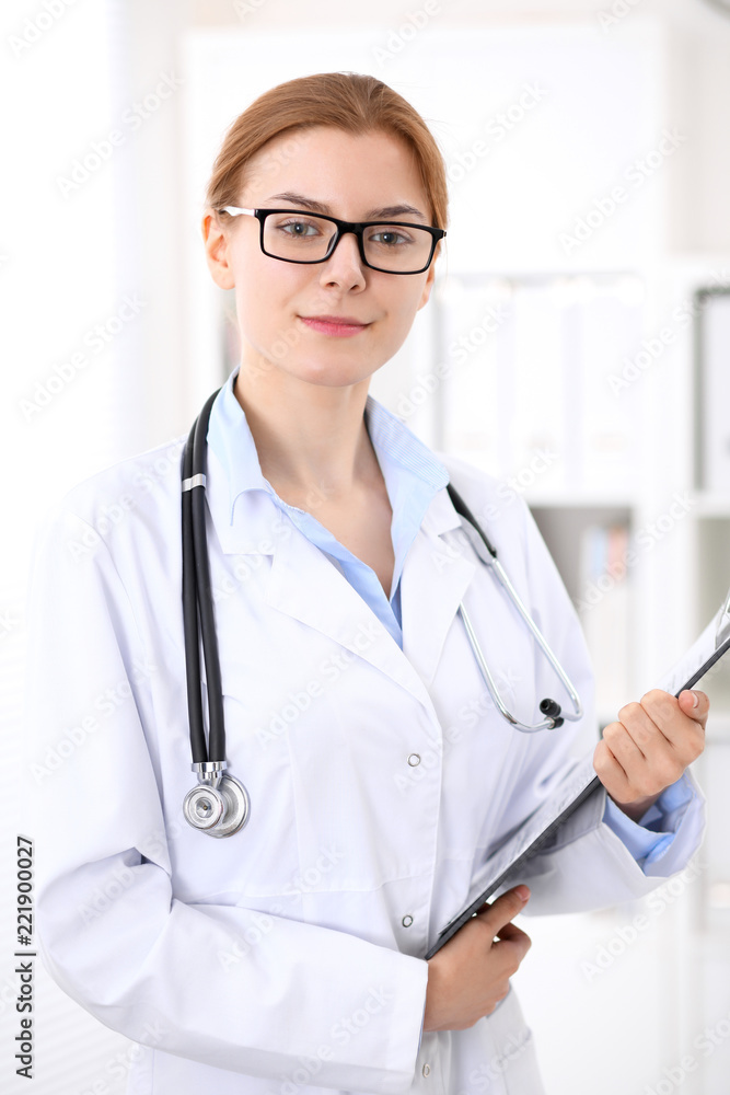 Young brunette female doctor at work in hospital. Physician ready to help. Medicine and healthcare concept Young brunette female doctor at work in hospital. Physician ready to help. Medicine and healthcare concept