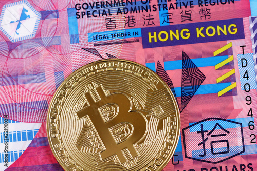 A macro image of a golden bitcoin with a 10 Hong Kong dollar bill
