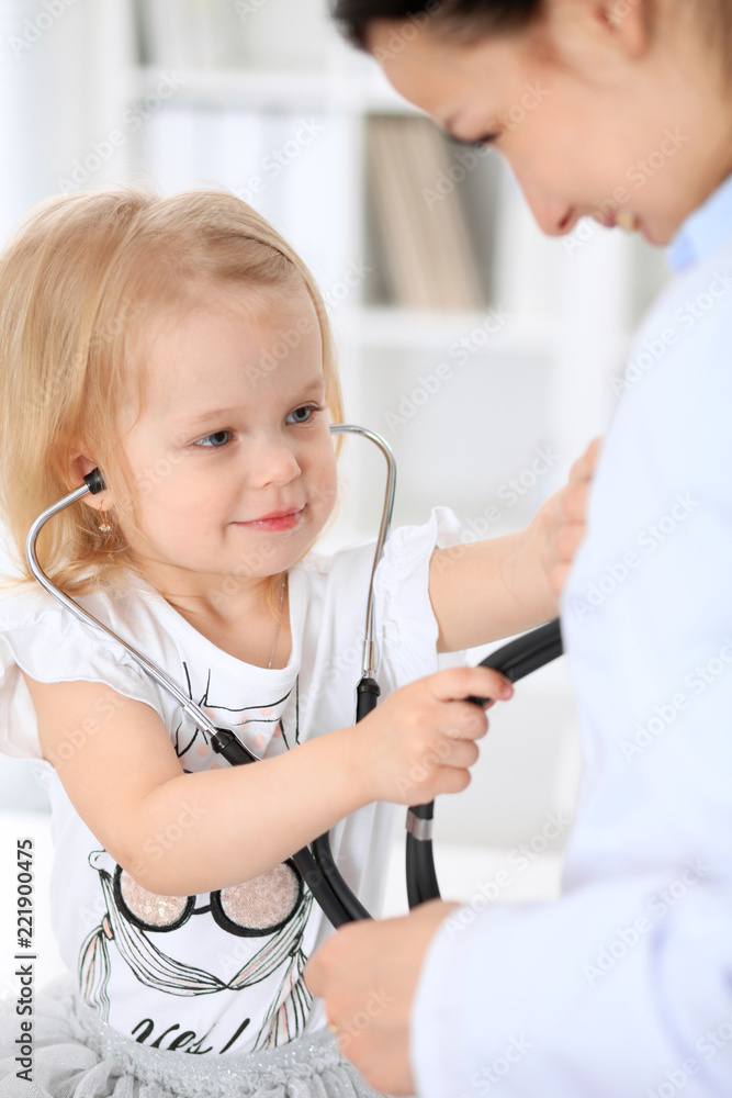 Doctor and patient baby in hospital. Little girl is being examined by pediatrician with stethoscope. Health care, insurance and help concept Doctor and patient baby in hospital. Little girl is being examined by pediatrician with stethoscope. Health care, insurance and help concept