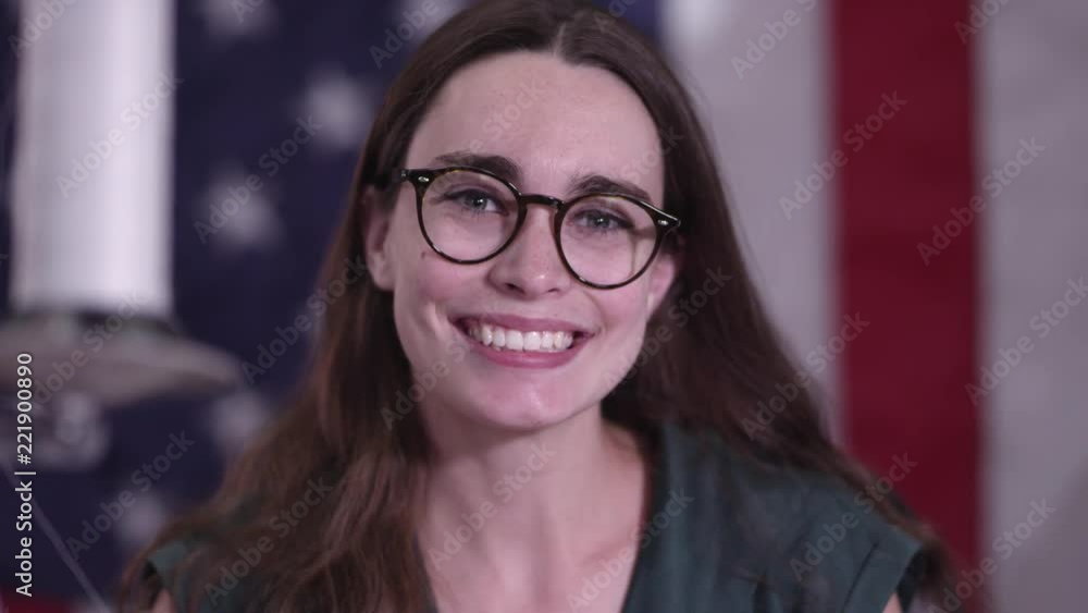 Young woman in front of American Flag smiling as she looks up. Young woman in front of American Flag smiling as she looks up.