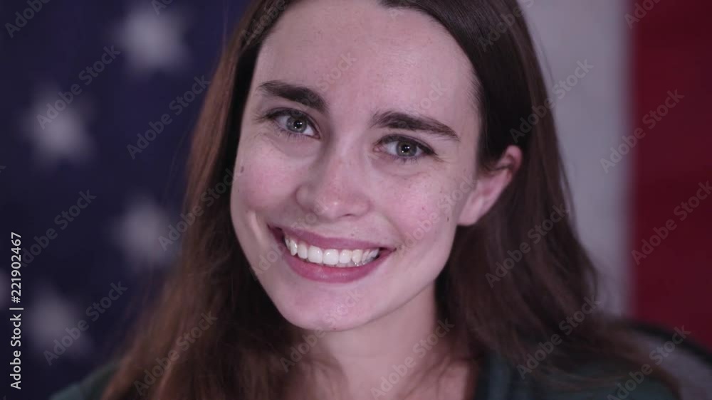 Young woman in front of American Flag smiling as she looks up. Young woman in front of American Flag smiling as she looks up.