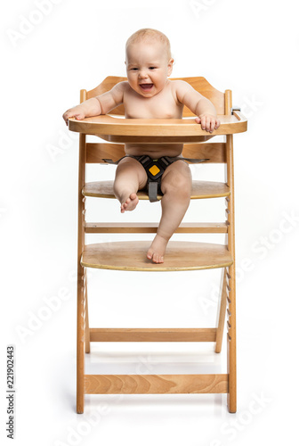 Happy cute baby girl sitting in high chair over white