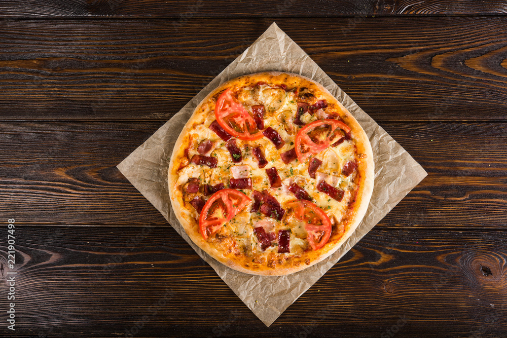 Small mini pizza (mini, miniature) on baking paper on a dark wooden background Small mini pizza (mini, miniature) on baking paper on a dark wooden background