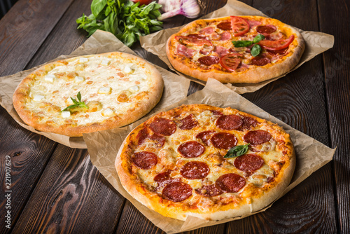 Small mini pizza (mini, miniature) on baking paper on a dark wooden background