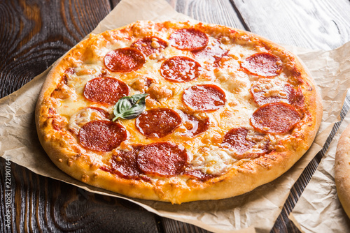 Small mini pizza (mini, miniature) on baking paper on a dark wooden background