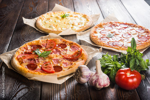 Small mini pizza (mini, miniature) on baking paper on a dark wooden background