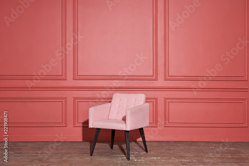 Nice soft pink armchair stands in studio