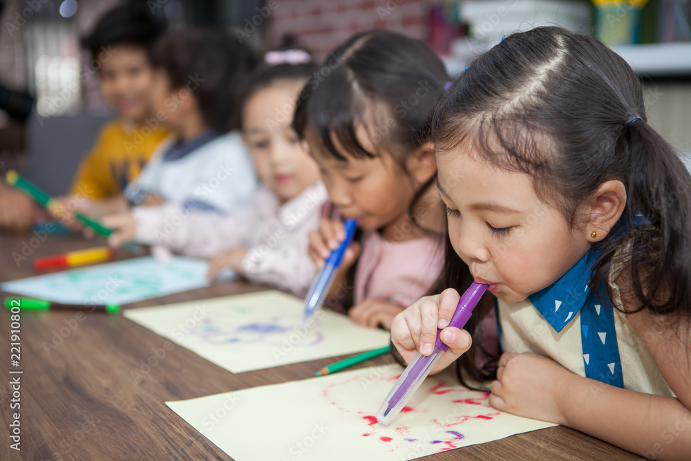 group of Cute little girl and boy student blowing color pen painting together with nursery teacher in classroom school . Happy children in a kindergarten . kid artist multiethnic group of Cute little girl and boy student blowing color pen painting together with nursery teacher in classroom school . Happy children in a kindergarten . kid artist multiethnic