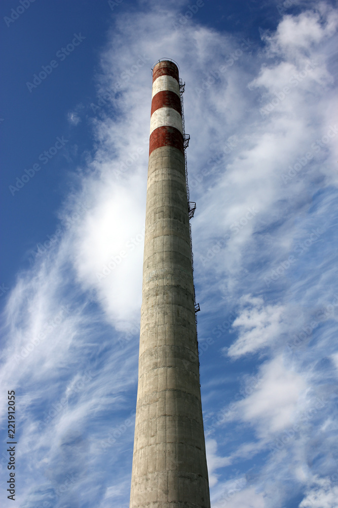 large factory concrete chimney. Steam escapes from the pipe against the sky. Industrial emissions of pollutants into the atmosphere.