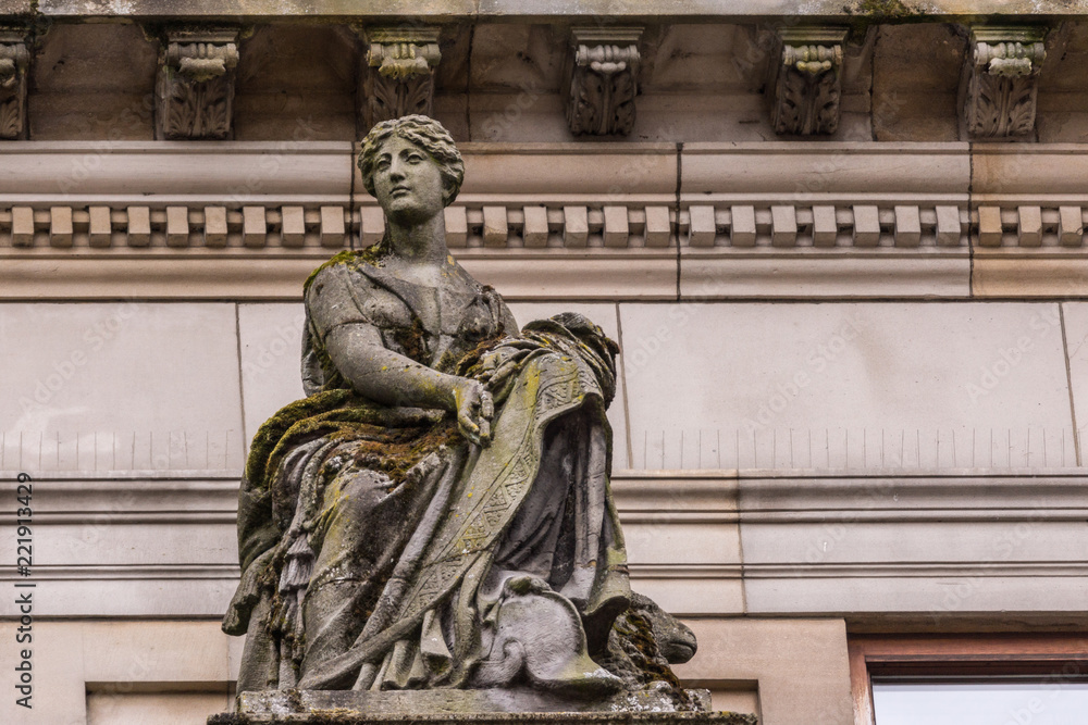 Obraz premium Glasgow, Scotland, UK - June 17, 2012: Closeup of brown stone and molded statue of sitting woman on facade of City Council building. Mostly shades of brown.
