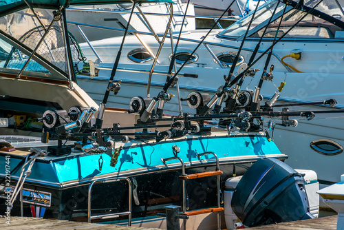 Fishing poles lined up along the back of a motor boat, concept, recreational boats in background