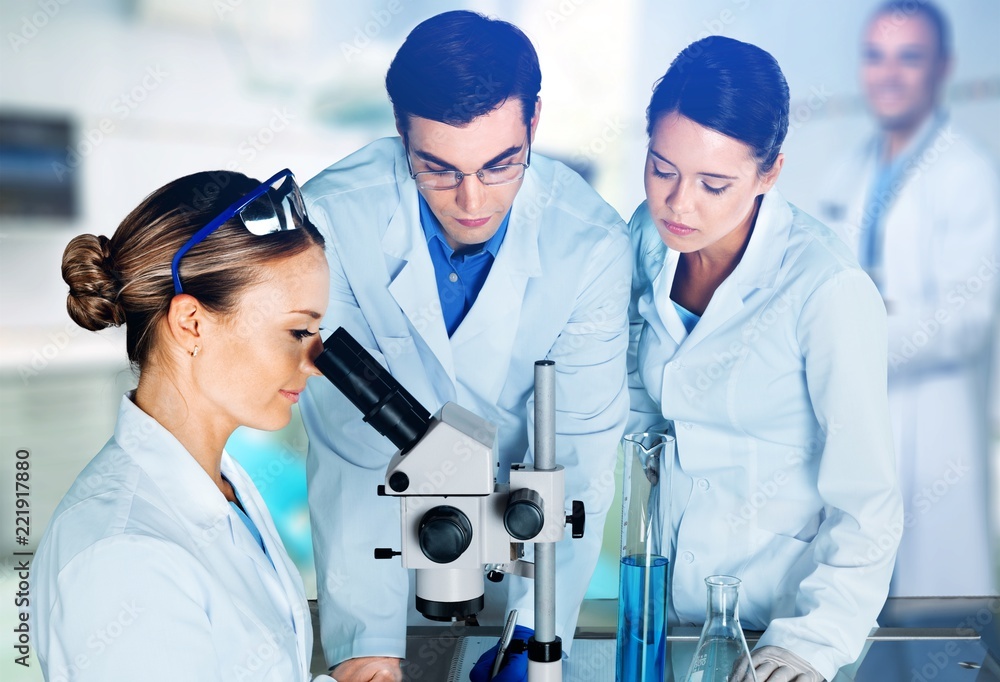 Female and male scientists in glasses working with microscope Female and male scientists in glasses working with microscope