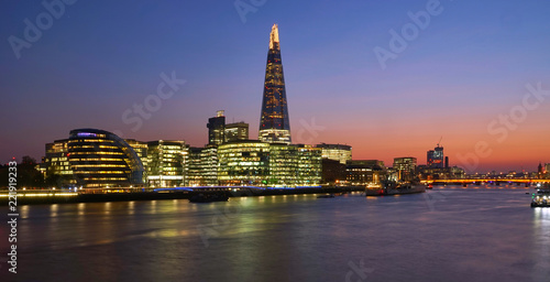 Cityscape Skyscraper of Modern Buildings include The Shard in Business District in South Bank during Twilight with Orange Shade of Sunset behind the Bridge over Thames River 