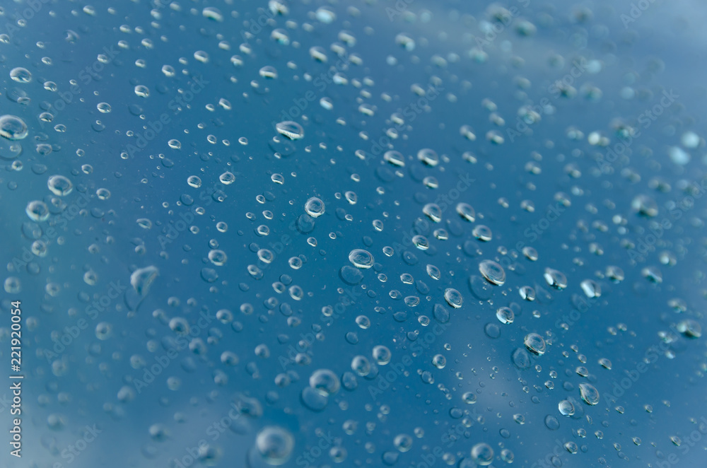 Drops of rain falling down on the car glass 