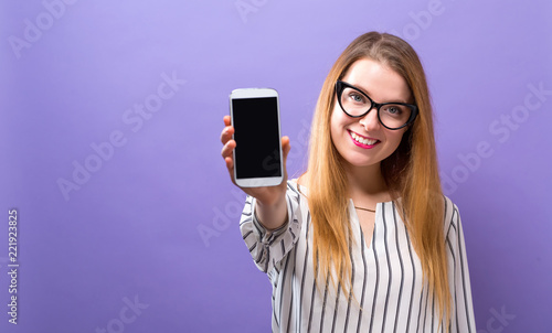 Young woman holding out a cellphone in her hand