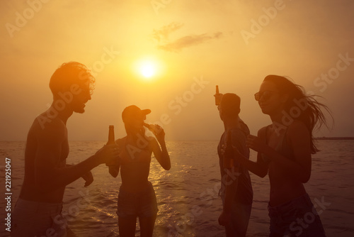 Wall Mural Group of friends celebrating and drinking at the beach in twilight sunset