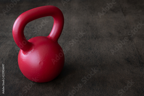Red kettlebell on a brown leather textured background
