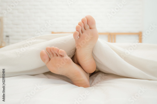 Close up two feet of woman sleep on white bed in bedroom,Feeling relax and comfortable,Healthcare Concept