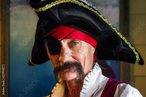 Pirate with an Eye Patch and One Piercing Eye Looks Intesly at the Camera He Has a Tripoint Hat and a Bandana