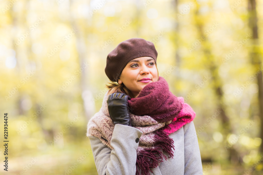 Autumn, nature, people concept - beautiful young woman in a grey coat and a beret standing in the park. Autumn, nature, people concept - beautiful young woman in a grey coat and a beret standing in the park.