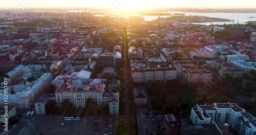 Aerial scenic view of Helsinki capital of Finland during sunrise. Drone coming down descending above rooftops filming straight street line of Bulevardi ending at morning sun. Scandinavia photo