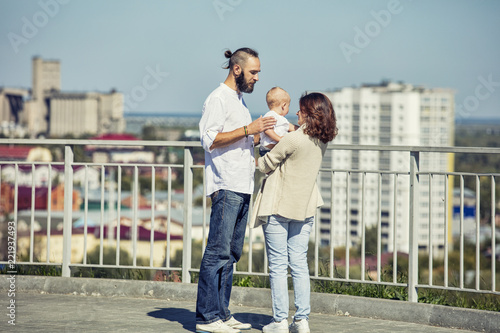 Family mom dad and baby happy with smiles together in the Park overlooking the city walking summer portrait