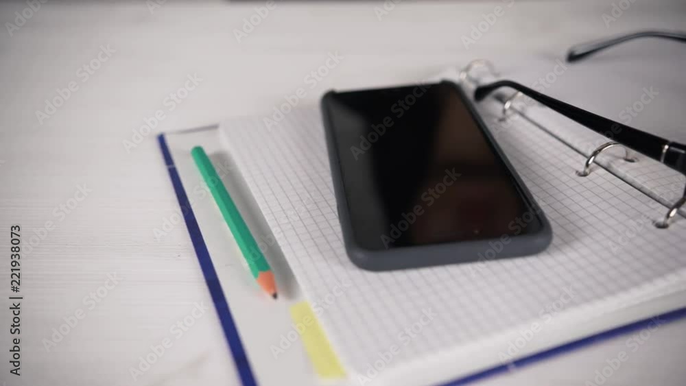 Girl sitting at a white table with glasses reading a book, diary. Bad eyesight. Girl sitting at a white table with glasses reading a book, diary. Bad eyesight.