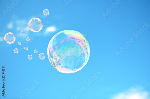 The beautiful soap bubbles with reflection and glare are in a blue sky.