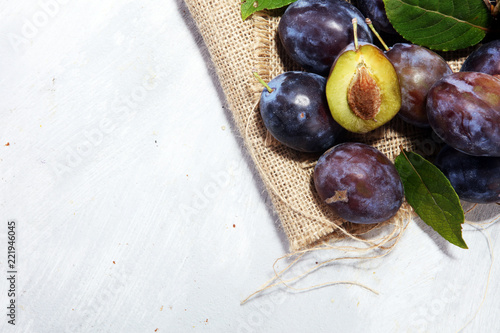 Plums on rustic background. Half of blue plum fruit. Many beautiful plums with leaves