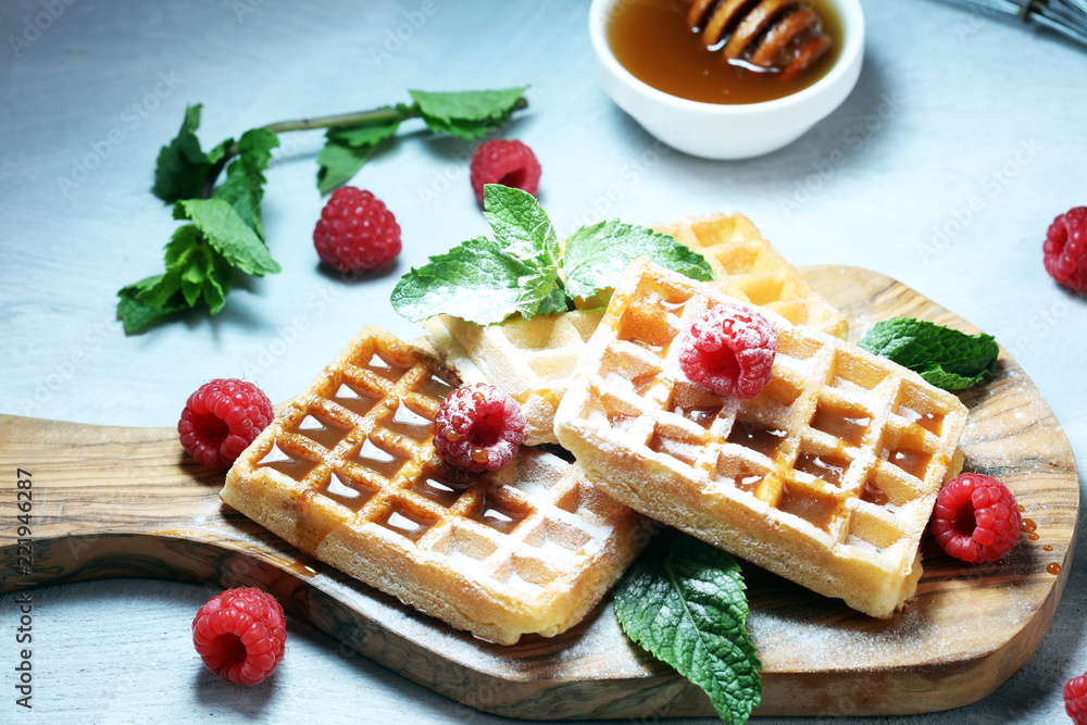 Traditional belgian waffles with fresh mint, sugar and raspberries. Traditional belgian waffles with fresh mint, sugar and raspberries.