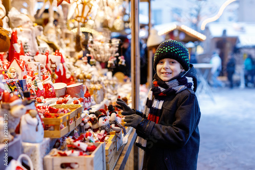 Little cute kid boy selecting decoration on Christmas market. Beautiful child shopping for toys and decorative ornaments © Irina Schmidt