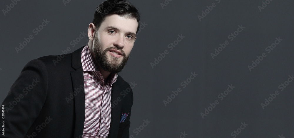 Obraz premium portrait of a stylish business man sitting on the back of a chair.isolated on grey background