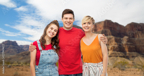 travel, tourism and summer holidays concept - group of happy smiling friends hugging over grand canyon national park background