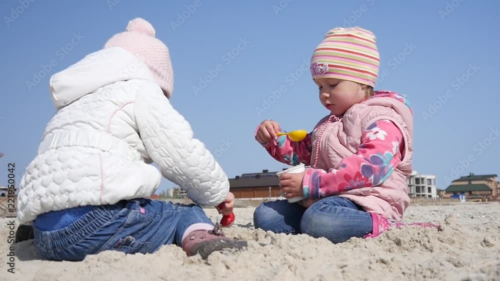 Two little kid girls playing with a sand on a sea shore Two little kid girls playing with a sand on a sea shore