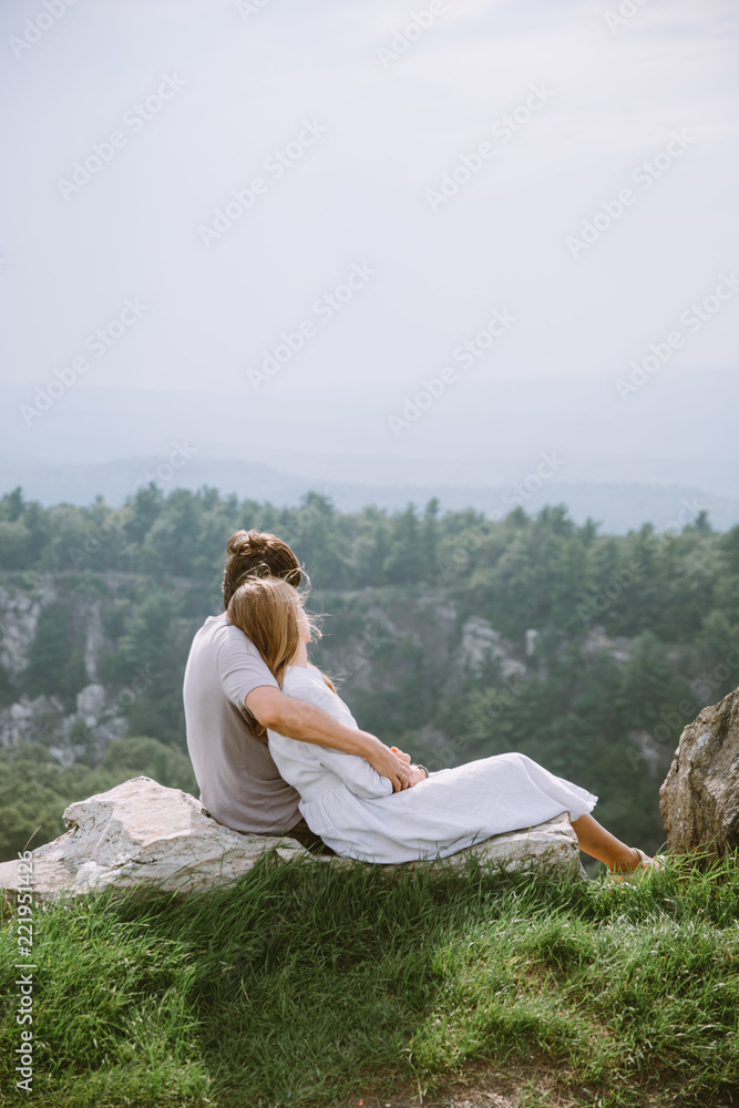 Young couple sitting on the edge of mountains with a beautiful view