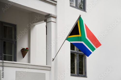 South Africa flag. South African flag hanging on a pole in front of the house. National flag of waving on a home displaying on a pole on a front door of a building. Flag raised at a full staff.