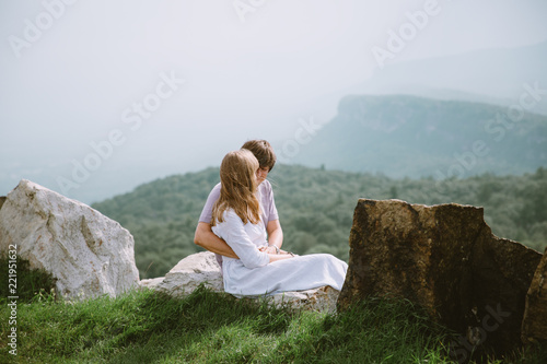 Young couple sitting on the edge of mountains with a beautiful view