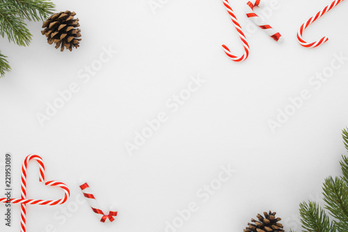 Christmas and New Year background. Christmas frame made of fir leaves, pine cone and candy cane on white background. Creative flat lay, top view design