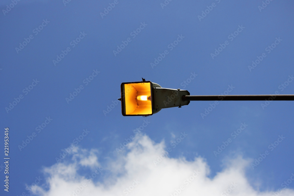 one city lantern on a concrete column lit a summer sunny day against a blue sky. one city lantern on a concrete column lit a summer sunny day against a blue sky.