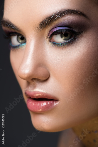 close up of young model with glitter makeup on face, isolated on grey
