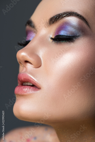 sensual young woman with closed eyes and glitter eyeshadows  isolated on grey