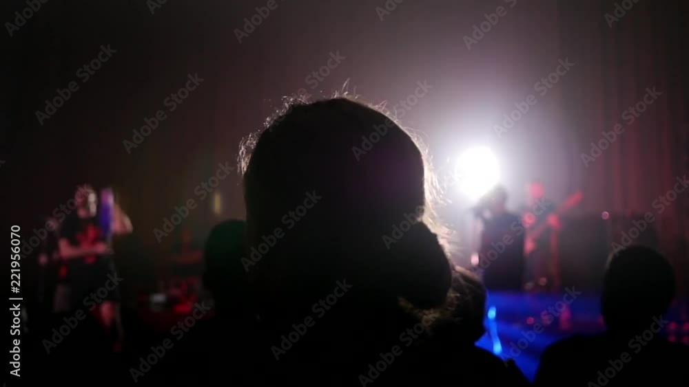 Fan spectator raising hands up in air enjoying music concert in light lumiere