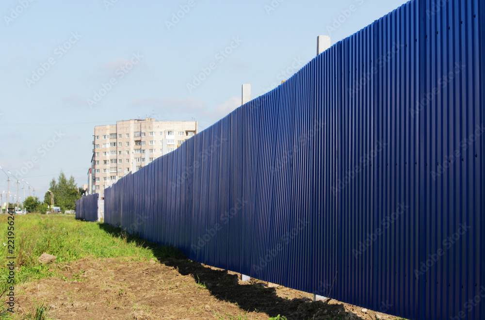 blue long construction fence, enclosing construction, where is new building of house with taking place