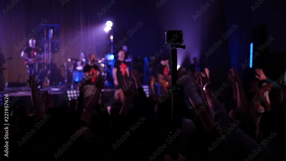 Crowd fan spectators silhouettes raise swaying hands at concert light lumiere