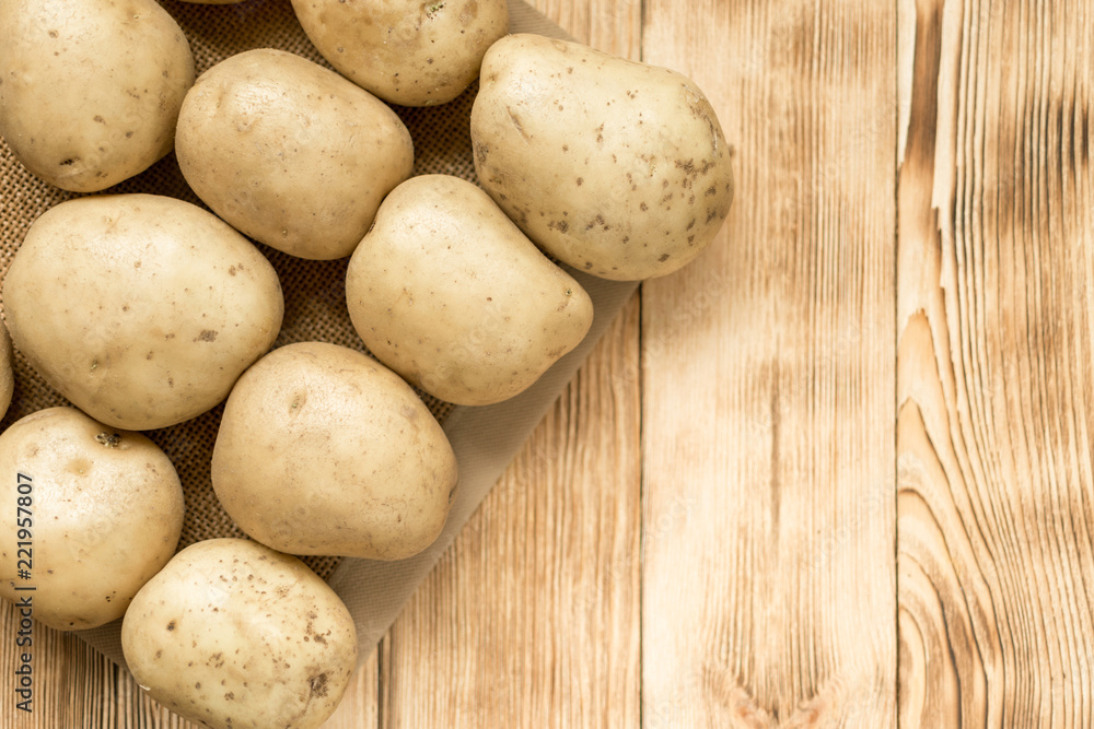 Raw potato tubers on a wooden background. Raw potato tubers on a wooden background.